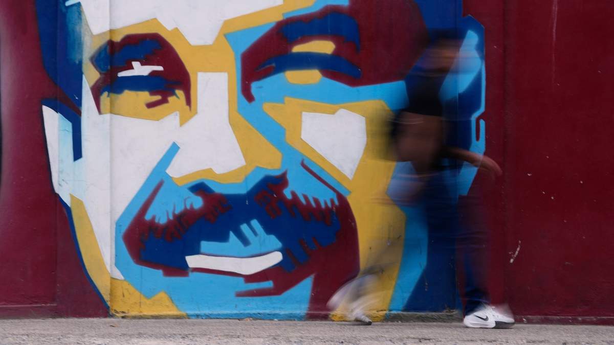 Un peatón pasa frente a un mural del presidente Nicolás Maduro