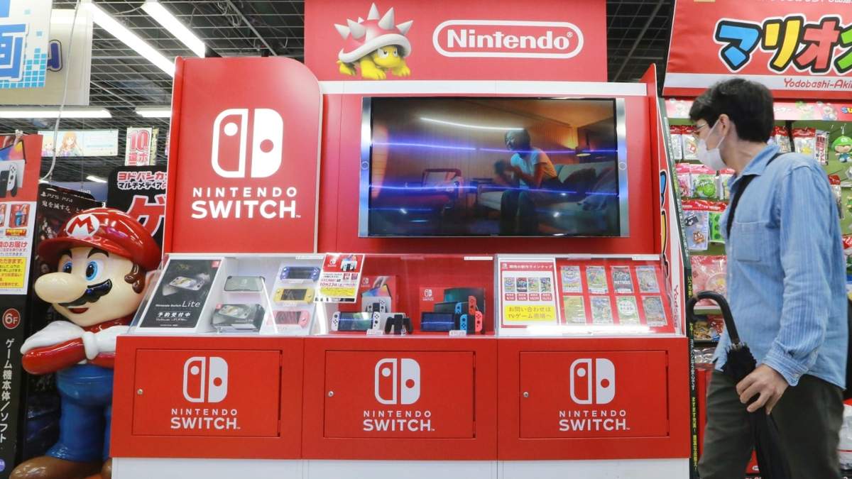 Un hombre camina junto a un expositor de Nintendo Switch en una cadena de tiendas de electrónica en Tokio