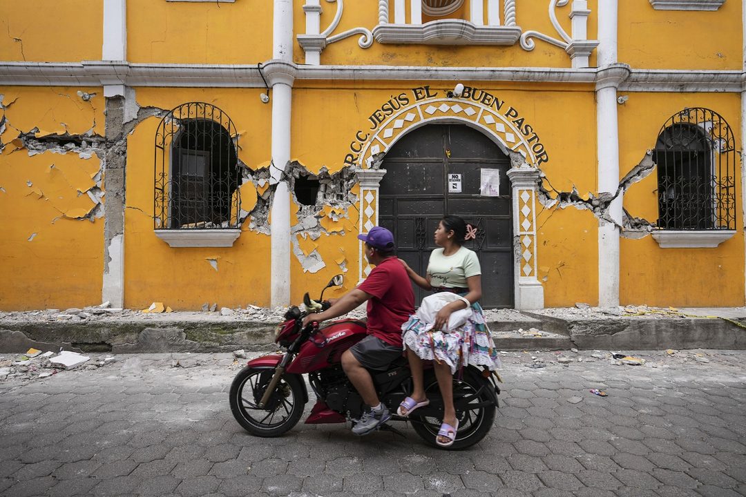 9 de julio. Una pareja pasa frente a un centro comunitario dañado tras una decena de sismos en Santa María de Jesús, Guatemala, en cuestión de horas. Foto APMoisés Castillo.