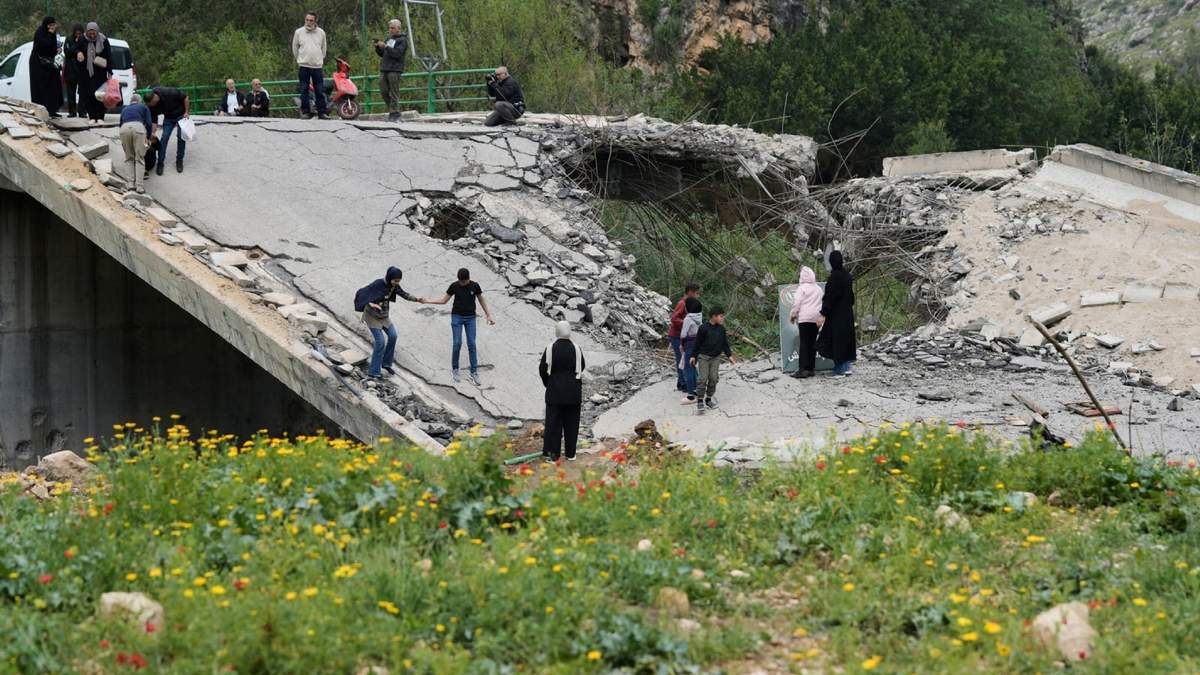Personas desplazadas cruzan un pie un puente destruido para regresar a sus pueblos tras un cese el fuego entre Hezbollah e Israel, en el poblado de Tayr Felsay, cerca de la ciudad de Tiro, en el sur de Líbano