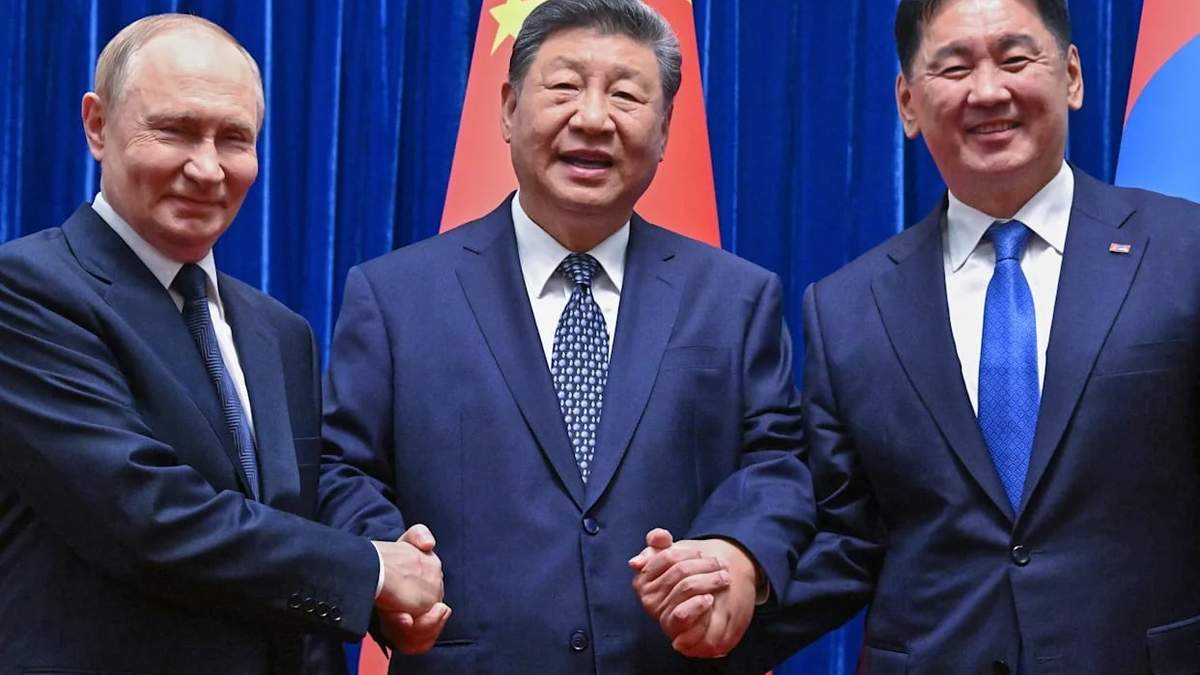 De izquierda a derecha, el presidente ruso, Vladímir Putin; el presidente de China, Xi Jinping, y el presidente de Mongolia, Ukhnaagiin Khurelsukh,estrechan las manos durante una sesión de fotos antes de su reunión trilateral en la sala Fujian en el Gran Salón del Pueblo en Beijing, China