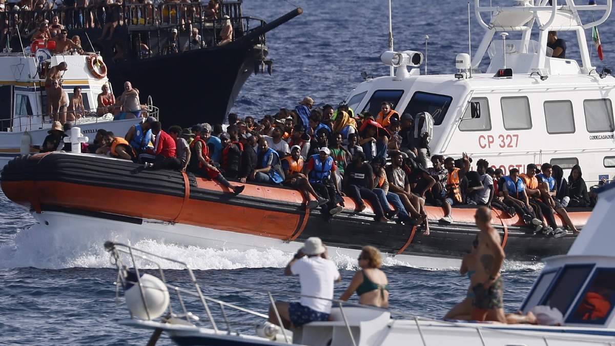 En la imagen, un barco de la Guardia Costera italiana transporta a los migrantes cerca del puerto de la isla siciliana de Lampedusa.