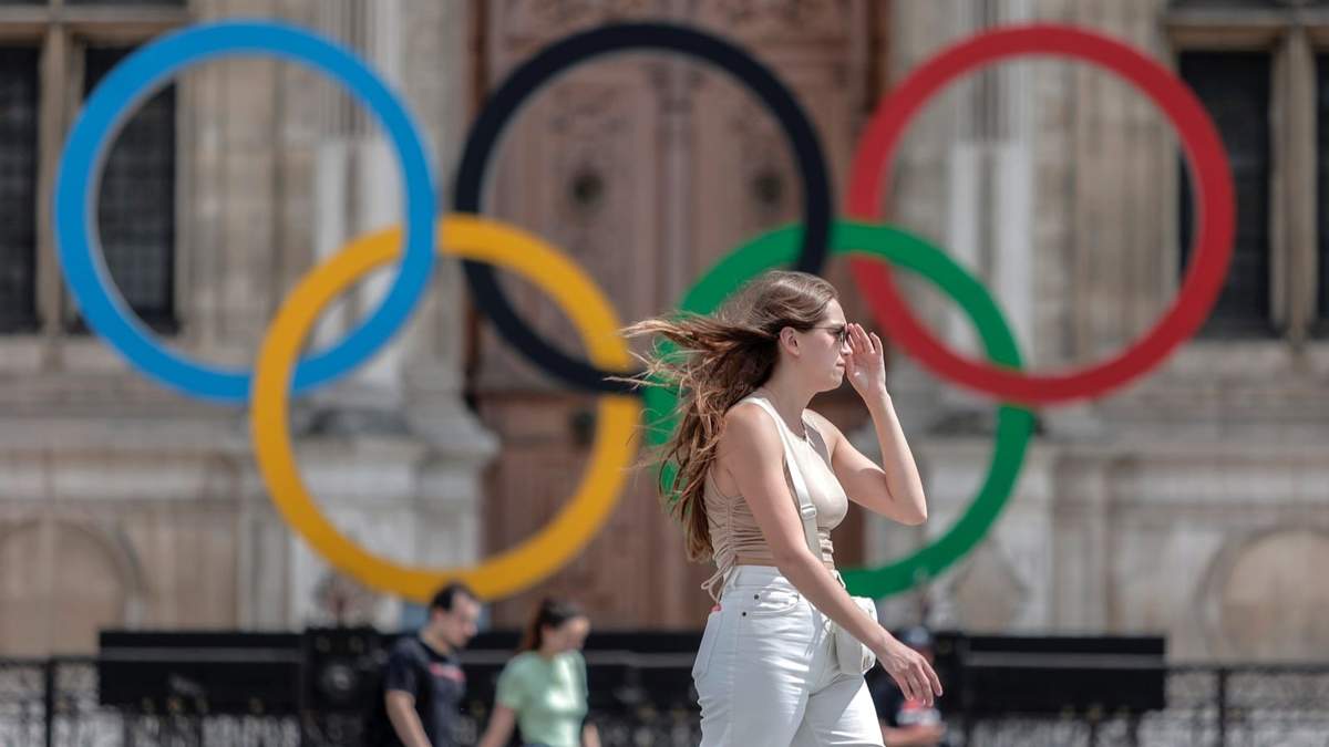 Una mujer pasa junto a los aros olímpicos afuera del ayuntamiento de París