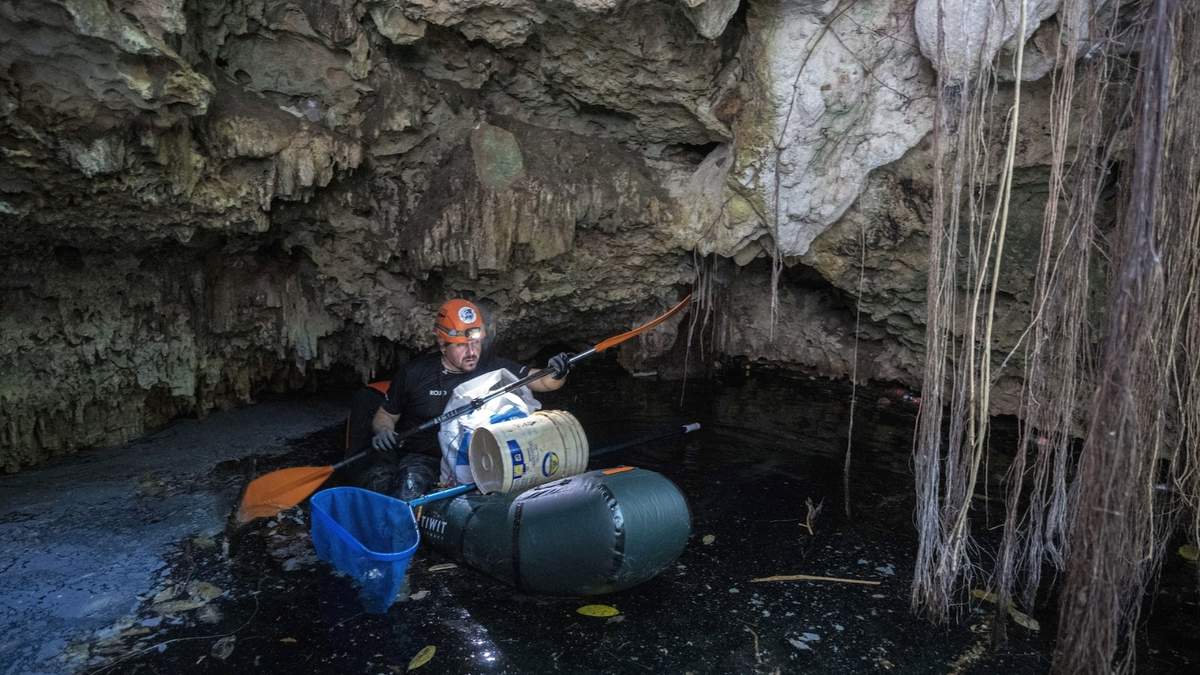 El biólogo Roberto Rojo rema en un cenote mientras recoge basura, el sábado 2 de marzo de 2024, en Playa del Carmen, México