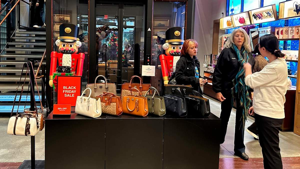Compradoras se detienen frente a bolsos de mano que son exhibidos en una tienda de la cadena Coach en Nueva York