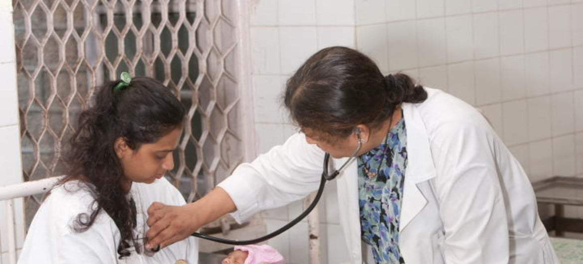 Un doctor examina a una madre con VIH y su bebé recién nacido en India.