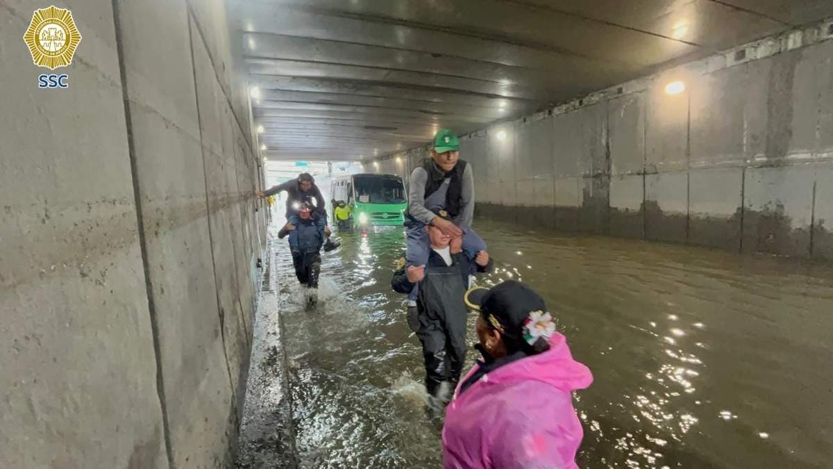 Pasajeros de transporte público son auxiliados por elementos de la SSC, después de que la unidad se quedó varada en un bajo puente de Río Churubusco a causa de una anegación por las lluvias de la madrugada del martes 2 de septiembre de 2025, en la CDMX