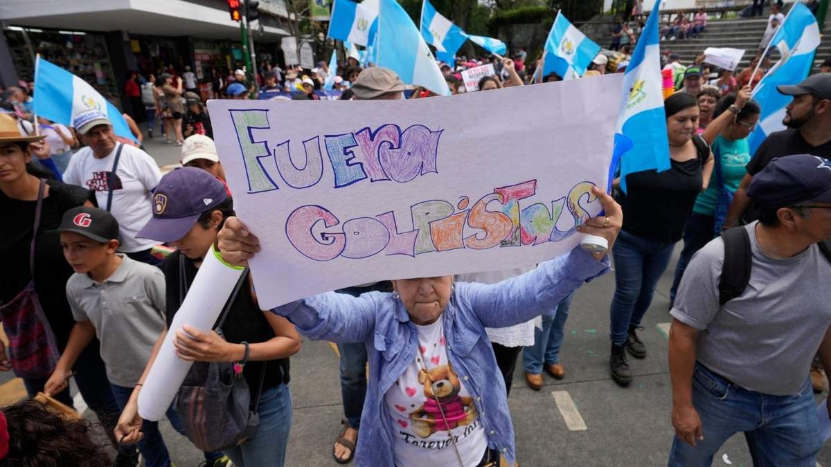 Una mujer sostiene un cartel durante una marcha contra las acciones legales emprendidas por la Fiscalía General contra el partido Movimiento Semilla y el presidente electo Bernardo Arévalo