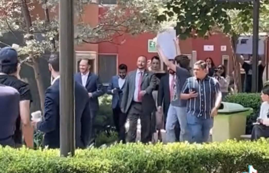 Un estudiante muestra una pancarta a la llegada del alcalde