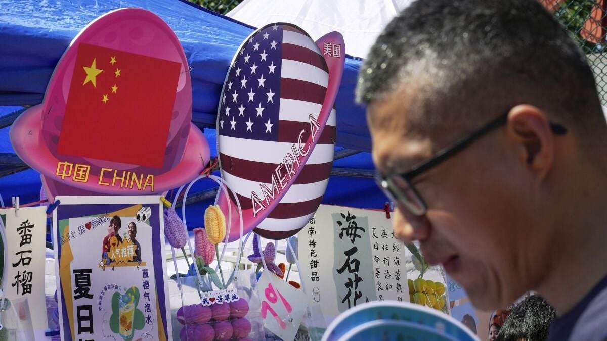 Hombre pasa por delante de un puesto de venta de comida y bebida con banderas de China y Estados Unidos
