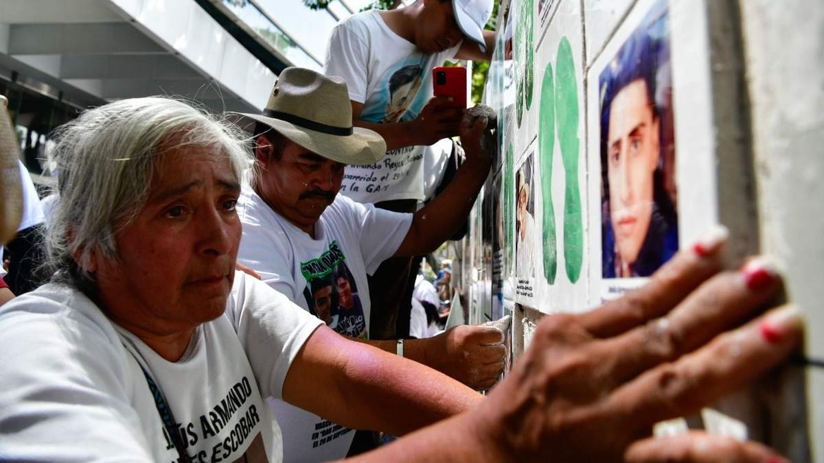 Familiares de personas desaparecidas pegan fichas de búsqueda