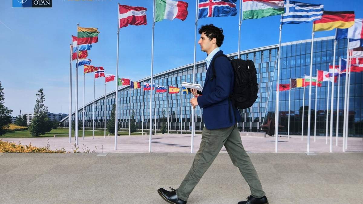 Un hombre camina ante un mural con una imagen de banderas de los miembros de la OTAN en Bruselas, el martes 23 de septiembre de 2025