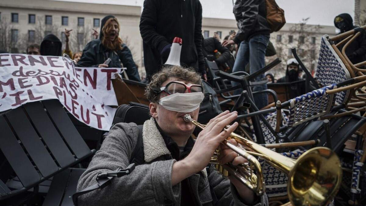 Un hombre toca la trompeta con los ojos tapados frente a una barricada durante una manifestación en Lyon, en el centro de Francia