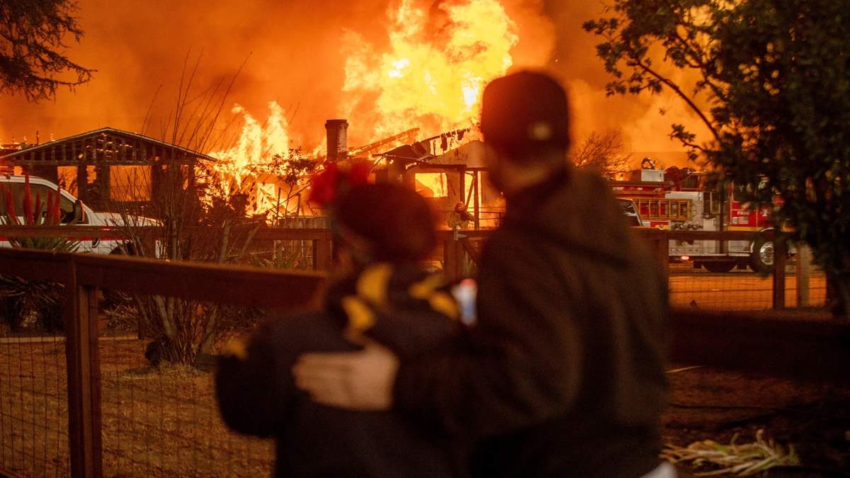 Personas observan una estructura quemándose en Altadena, California