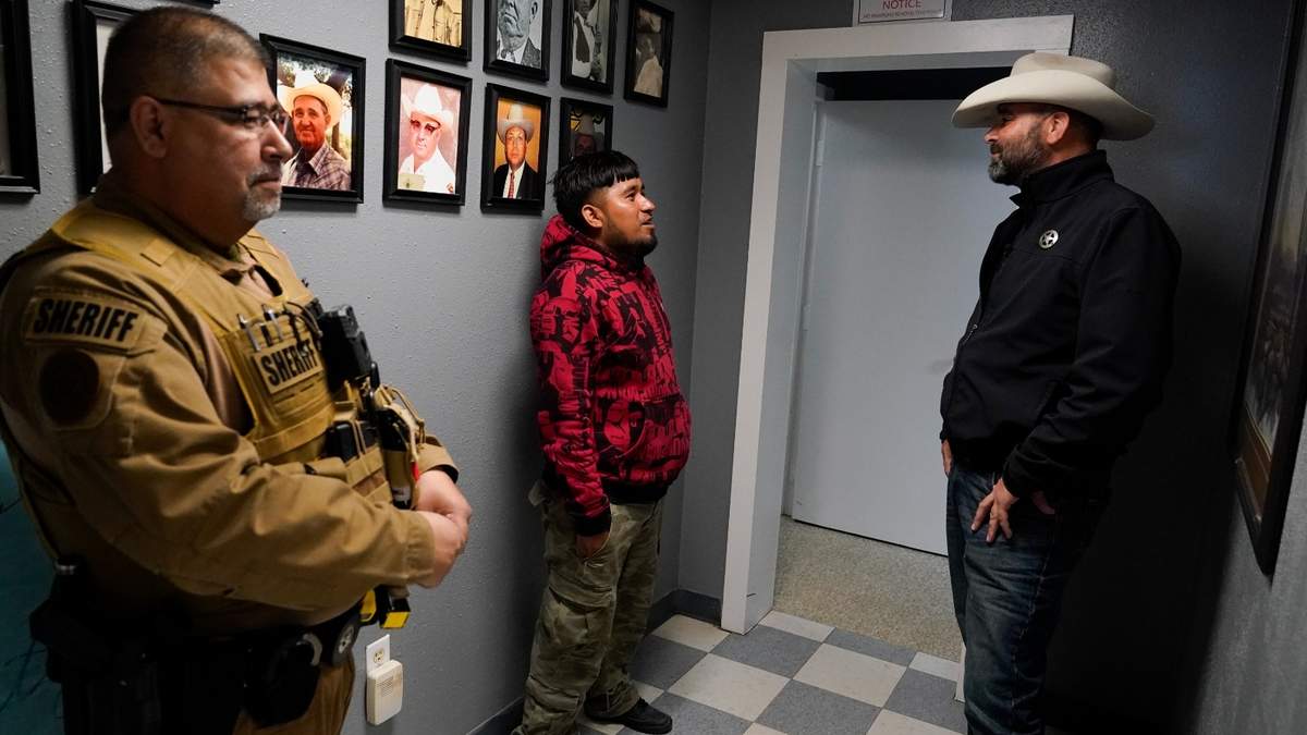 El jefe de policía del condado Terrell, Thaddeus Cleveland, habla con un migrante mexicano recientemente detenido