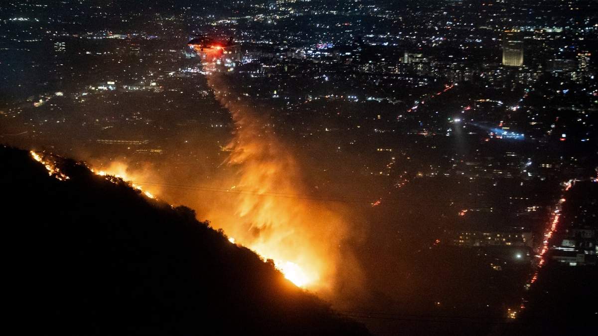 Un helicóptero rocía agua sobre el incendio Sunset Fire en la sección Hollywood Hills de Los Ángeles