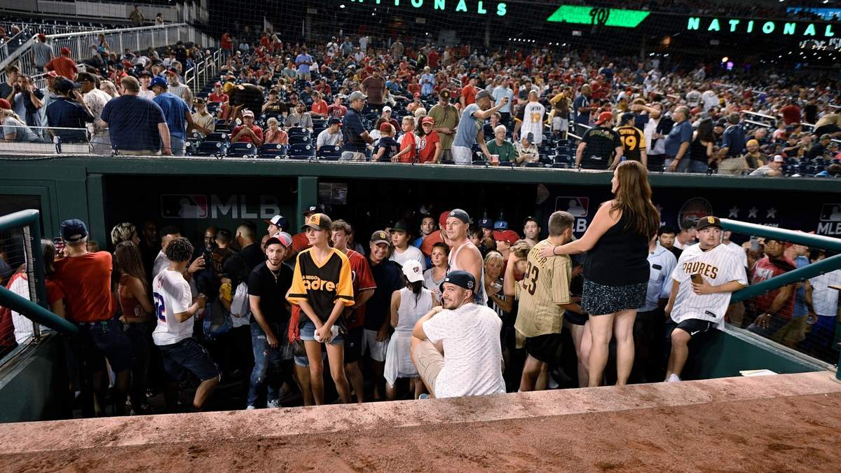 Aficionados se refugiaron en el área del equipo visitante tras el tiroteo afuera del estadio de los Nacionales de Washington.