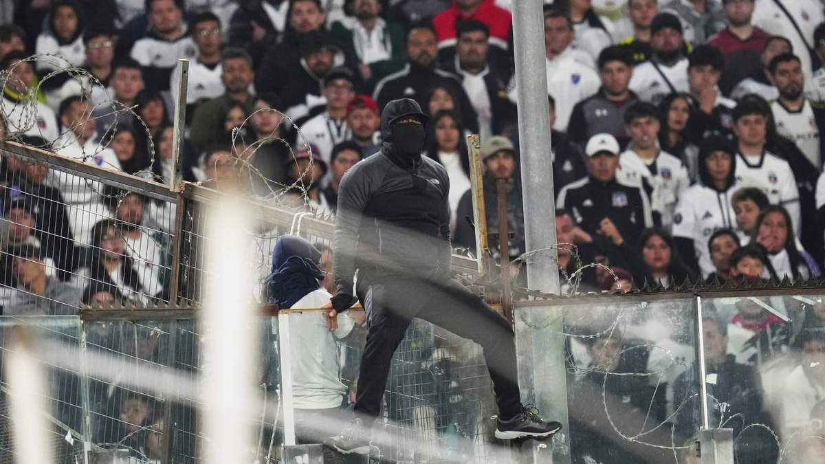 Un hincha trepa en un panel de cristal durante un partido de la Copa Libertadores entre Colo Colo de Chile y Fortaleza de Brasil en Santiago