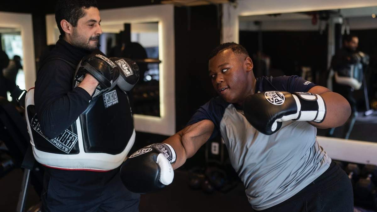 John Simon, un adolescente que se sometió a una cirugía bariátrica en 2022, hace ejercicio con su entrenador Chris Robles en El Workout Fitness en Los Ángeles