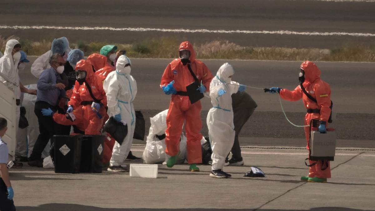 Los pasajeros son rociados con desinfectante por funcionarios del gobierno español antes de abordar un avión tras desembarcar del crucero MV Hondius, afectado por el hantavirus, en el aeropuerto de Tenerife,