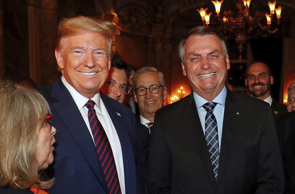 ARCHIVO - El expresidente brasileño Jair Bolsonaro, derecha, sonríe junto a Donald Trump durante una cena en Mar-a-Lago, Palm Beach, Florida, el 7 de marzo de 2020. El hijo de Bolsonaro, Eduardo, aparece al fondo a la derecha
