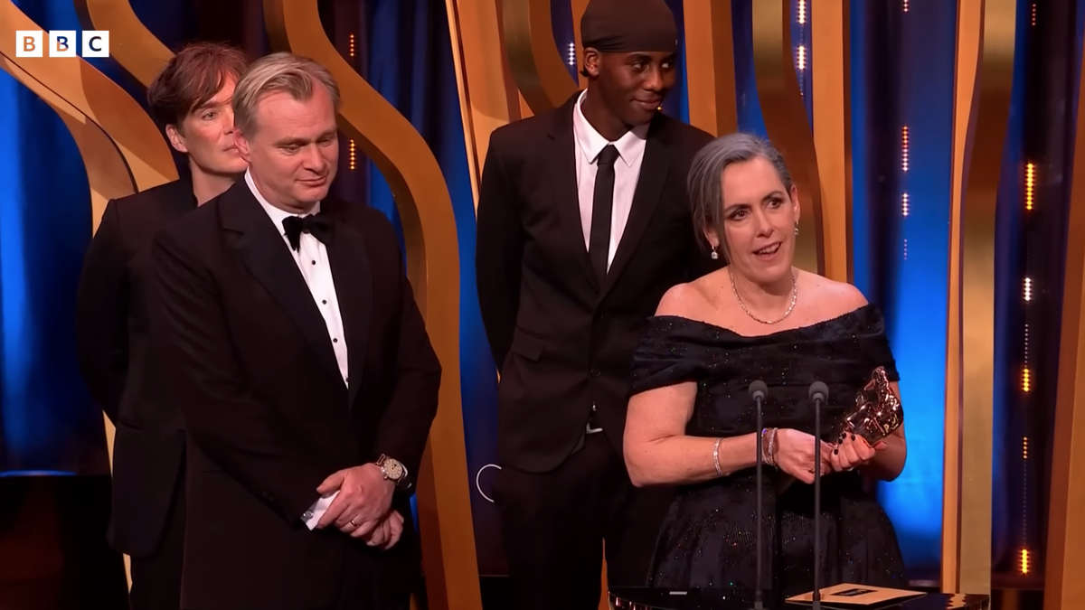 El youtuber Lizwani (con gorra) sonríe mientras habla Emma Thomas y escuchan Cillian Murphy y Christopher Nolan