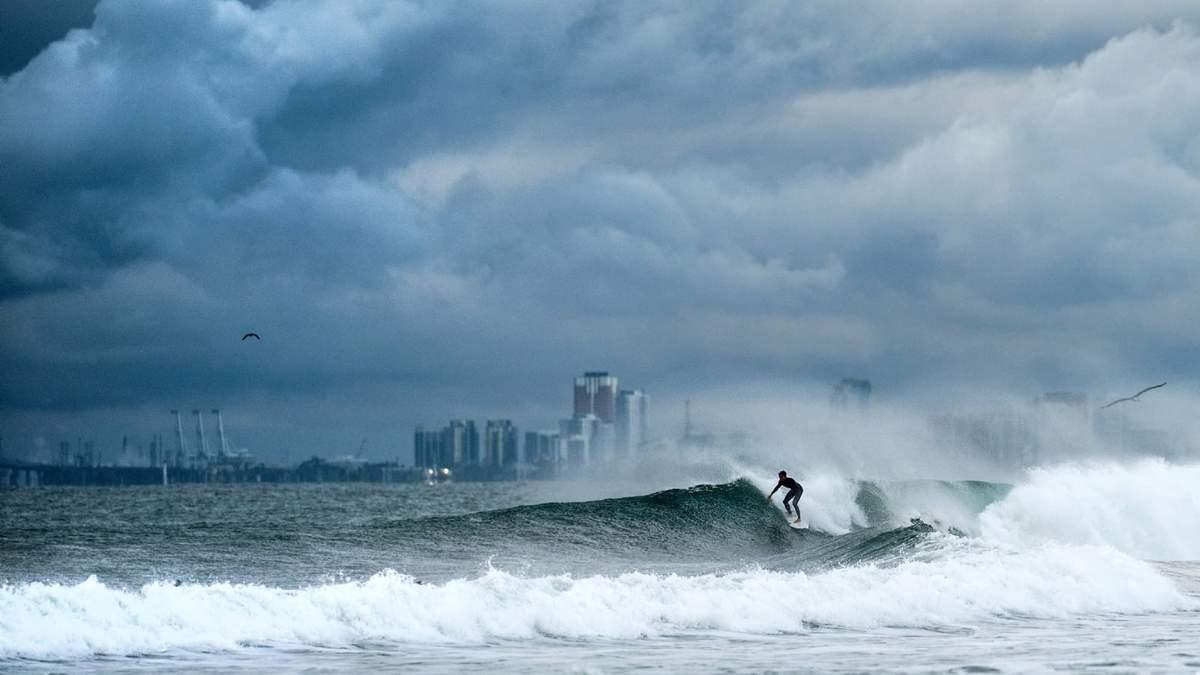 Un surfista monta una ola mientras se forman nubes en la playa estatal de Bolsa Chica, en el condado de Orange, California, el sábado 15 de noviembre de 2025