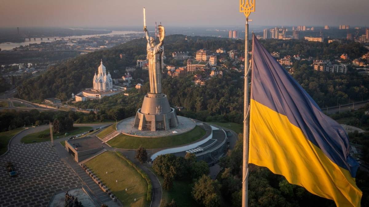 La bandera ucraniana ondea mientras trabajadores instalan el escudo del país en la estatua más alta del país, la estatua de la Madre Ucrania