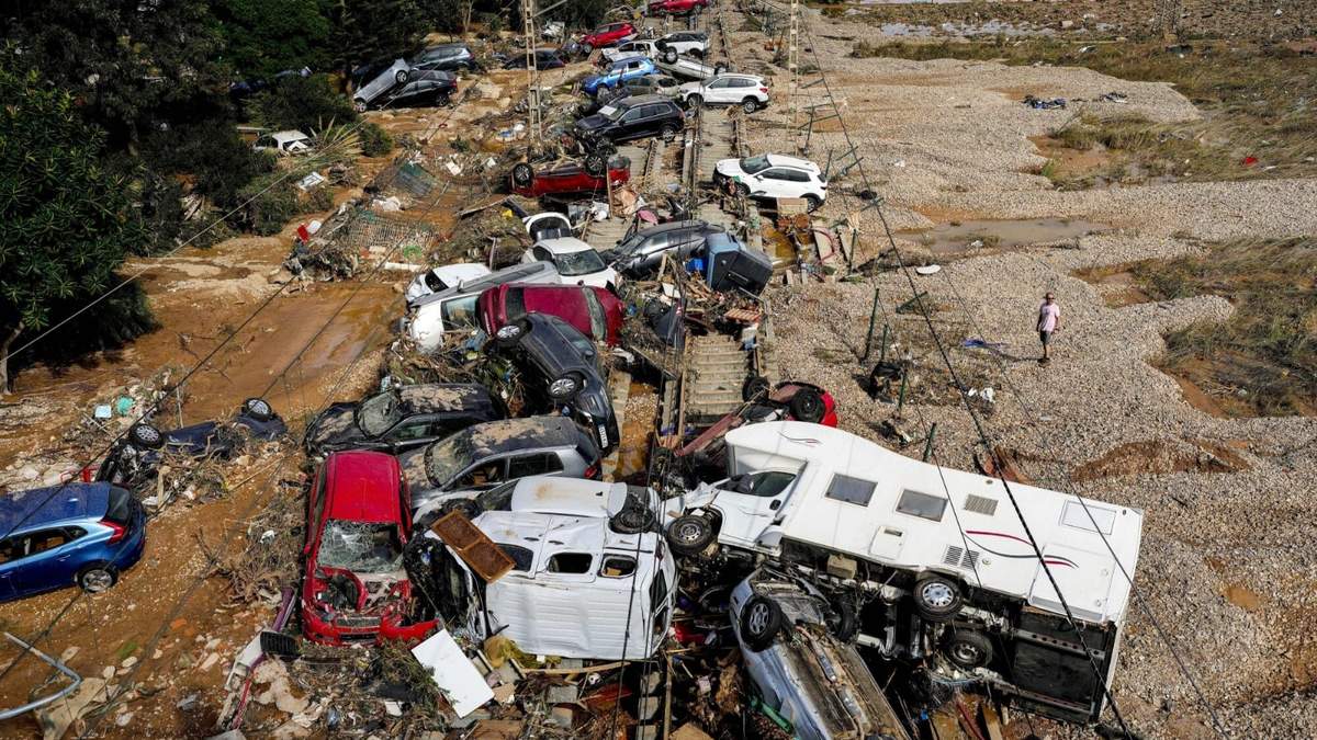 Un hombre se ve de pie junto a autos amontonados sobre unas vías por una inundación en Valencia, España