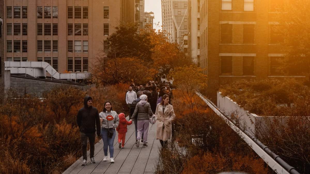Personas caminan por las calles y disfrutan de un atardecer en la ciudad