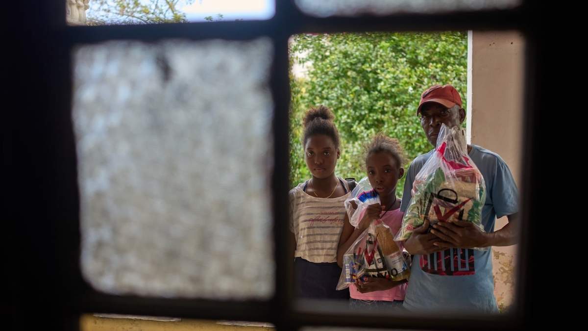 Guillermo Beltrán, beneficiario de la ayuda humanitaria mexicana, posa para una foto con sus hijas sosteniendo los artículos donados
