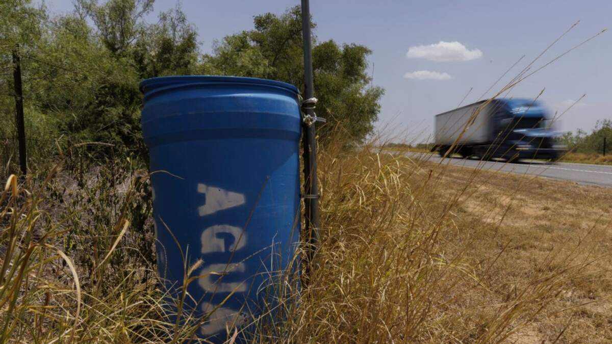 Una estación de agua para inmigrantes que contiene dentro bidones sellados de agua está ubicada al lado de una cerca próxima a una carretera en el condado rural Jim Hogg, en Texas