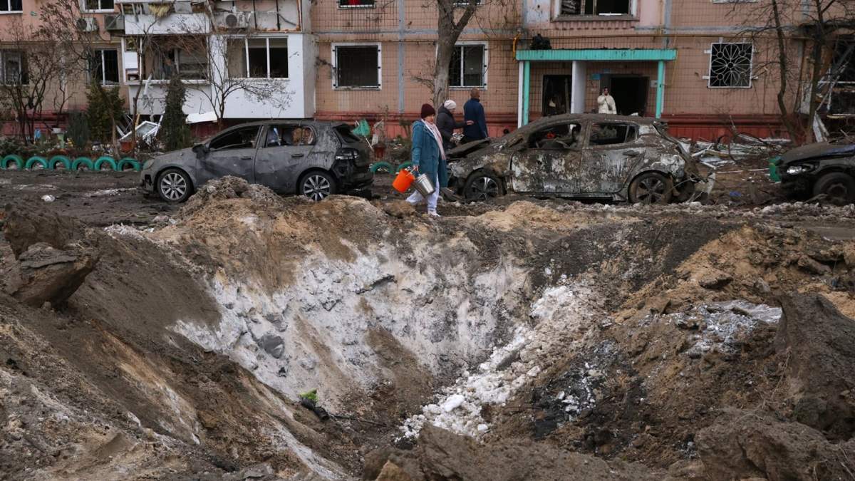 Varias personas pasan frente a un cráter y autos dañados cerca de un edificio de apartamentos tras un ataque ruso en Zaporiyia, Ucrania, el miércoles 28 de enero de 2026
