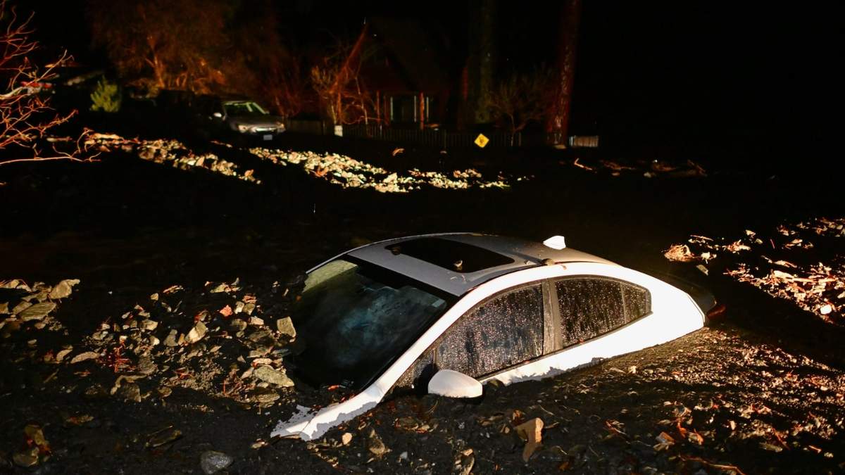 Un auto se ve enterrado en lodo tras una inundación el miércoles 24 de diciembre en Wrightwood, California