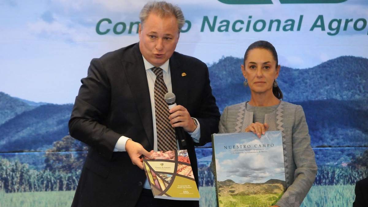 Juan Cortina Gallardo, titular del Consejo Nacional Agropecuario, le entrega dos libros a Claudia Sheinbaum