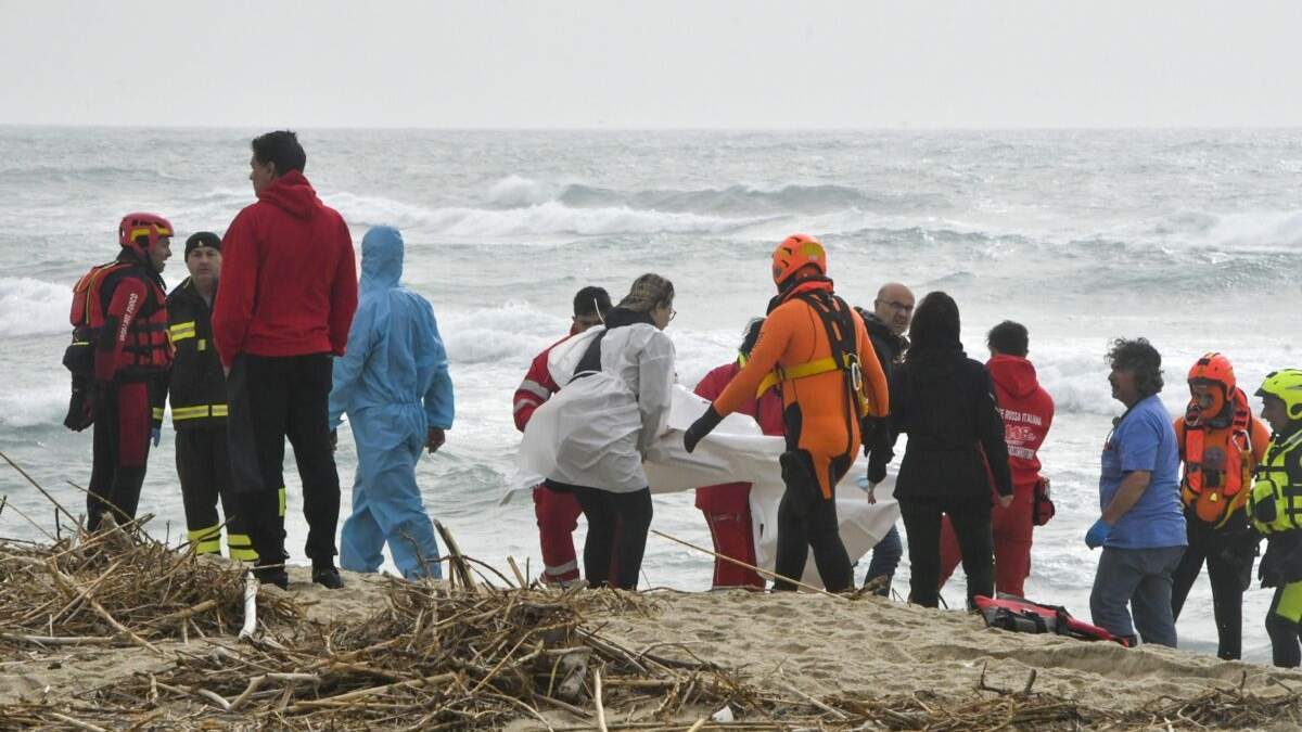 Rescatistas recuperan un cadáver de una playa cercana a Cutro, en el sur de Italia, el domingo 26 de febrero de 2023, después de que un bote de migrantes se partió en un mar picado