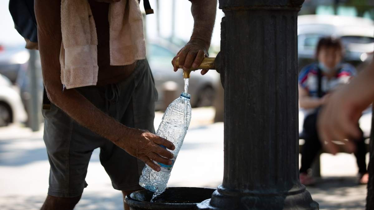 Un hombre rellena una botella de agua en una fuente en el parque de la Barceloneta