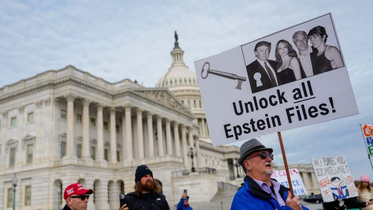 Manifestantes portan pancartas durante una conferencia de prensa sobre la Ley de Transparencia de los Archivos Epstein