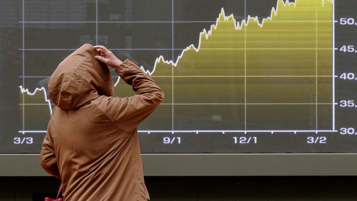 Una persona mira una pantalla con una gráfica del índice bursátil japonés Nikkei en una correduría en Tokio, el lunes 23 de marzo de 2026