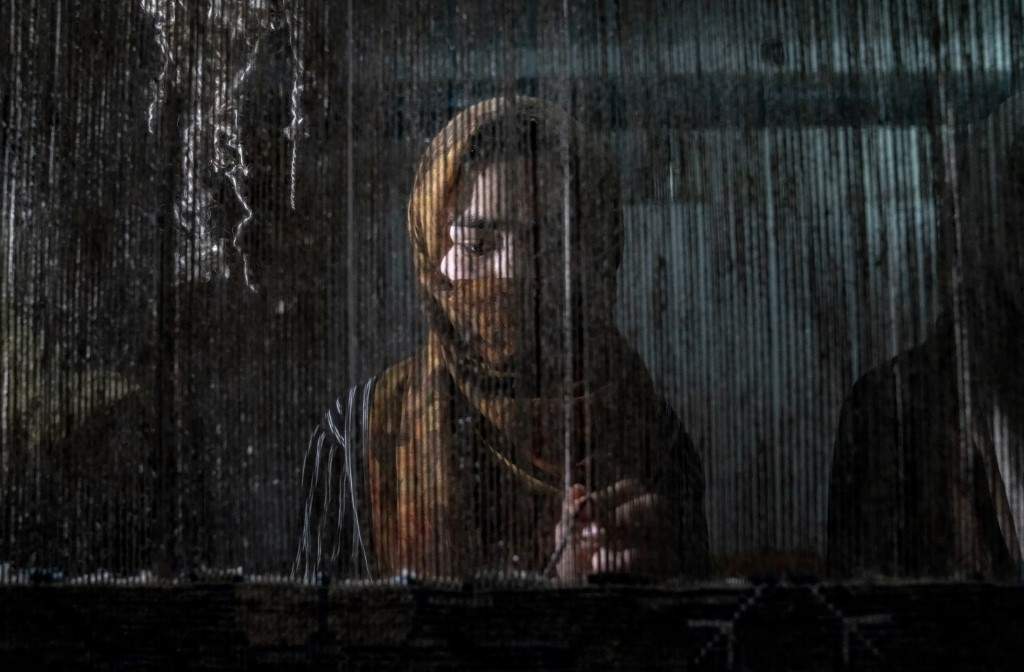 Una mujer afgana teja una alfombra en un fábrica tradicional en Kabul, Afganistán
