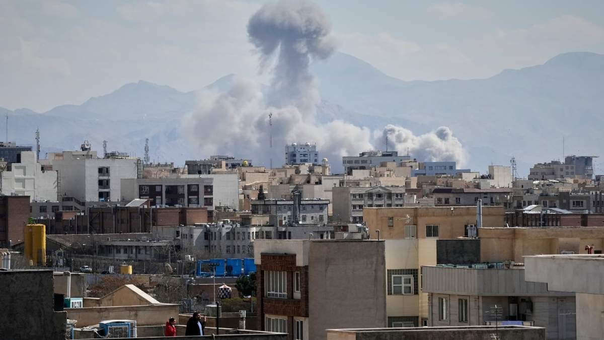 La gente observa desde una azotea cómo se eleva una columna de humo tras un ataque en Teherán, Irán, el domingo 1 de marzo de 2026