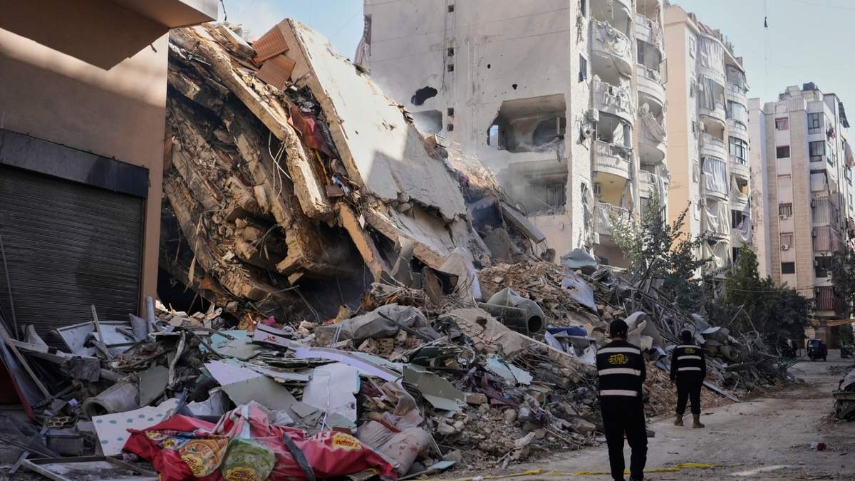 Miembros de Hezbollah caminan frente a un edificio destruido por un ataque aéreo israelí en Dahiyeh, en los suburbios del sur de Beirut, Líbano
