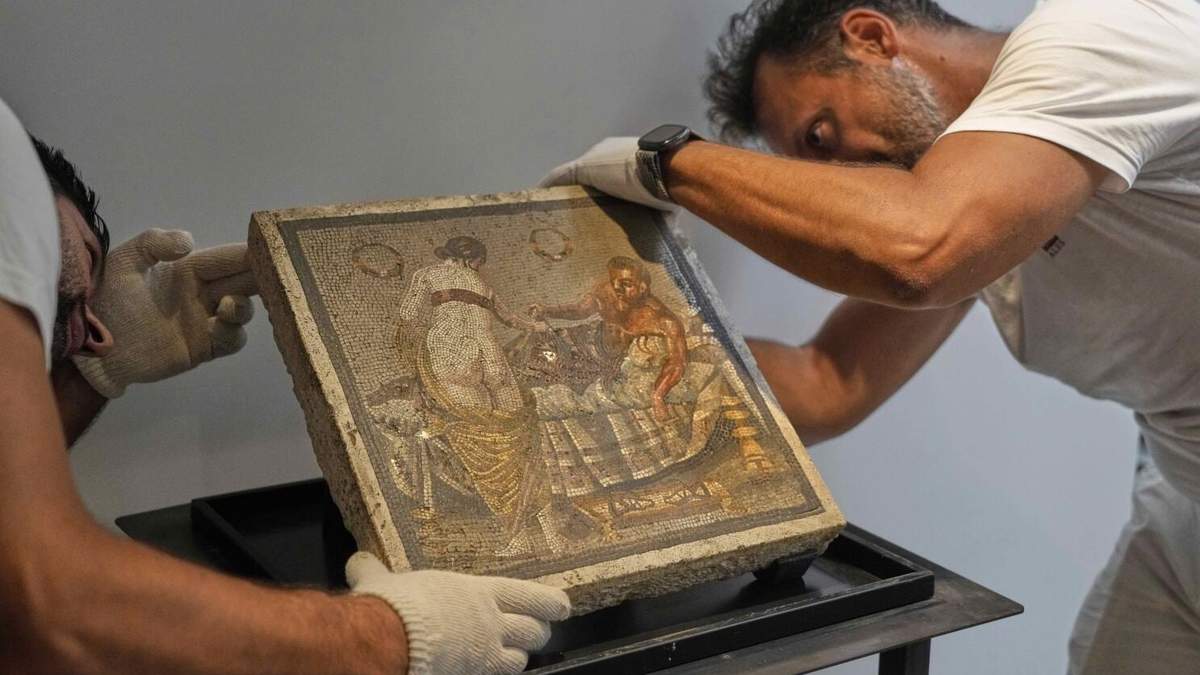 Restauradores exhiben un mosaico romano que representa a una pareja de amantes, que fue repatriado desde Alemania, en el parque arqueológico de Pompeya, Italia, el martes 15 de julio de 2025.