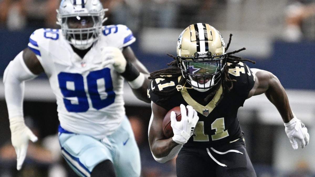 Alvin Kamara (41), running back de los Saints de Nueva Orleans, se escapa ante la mirada lejana de DeMarcus Lawrence (90), defensive end, en camino a una anotación en espectacular escapada en la primera mitad del juego de la NFL, el domingo 15 de septiembre de 2024, en Arlington, Texas