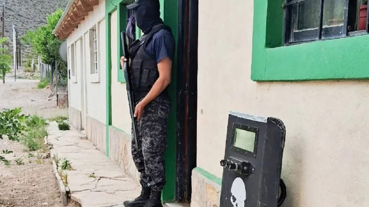 Un efectivo policial fuertemente armado en el acceso a la vivienda allanada. Fuente (Neuquén Informa)