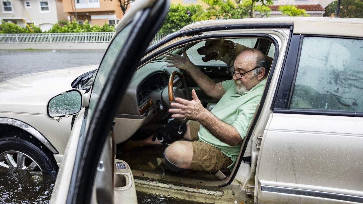 Mike Viesel y su perro Humi esperan dentro de su auto inundado a ser remolcados en Hollywood, Florida