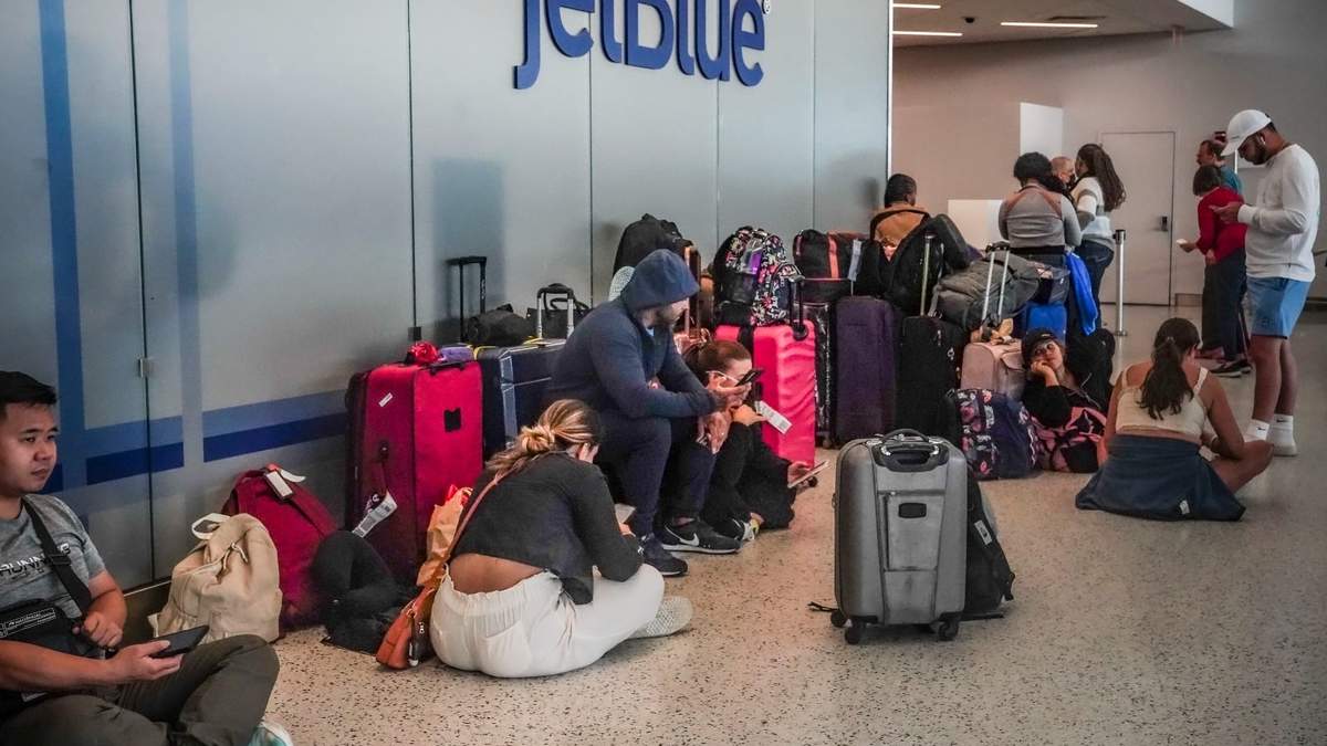 Viajeros sentados junto a su equipaje esperando en el área de revisión del Aeropuerto Internacional John F. Kennedy de Nueva York