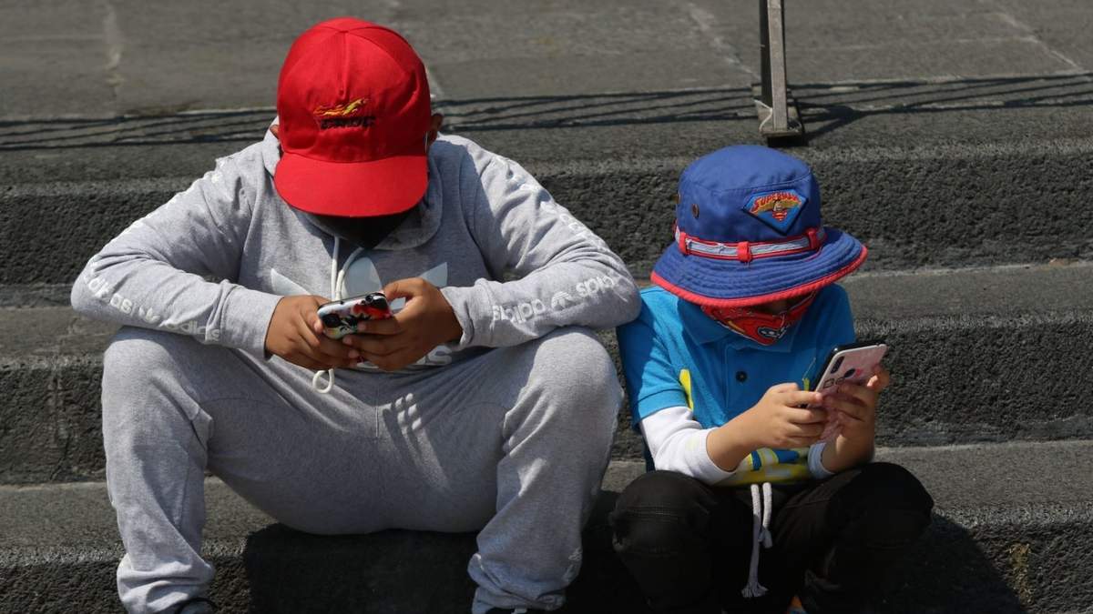 Un par de niños se entretienen con sus respectivos celulares
