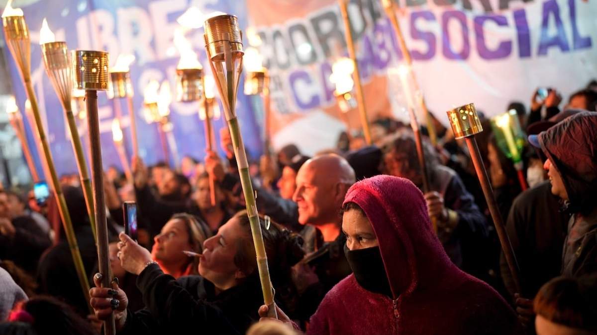 Integrantes de organizaciones sociales marchan con antorchas en protesta contra las políticas gubernamentales