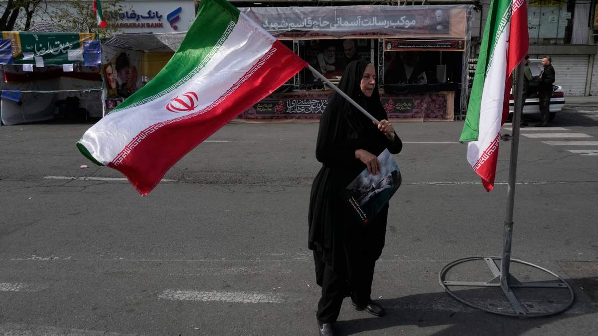 Una mujer ondea una bandera iraní durante una campaña a favor del gobierno en la plaza de la Revolución Islámica en el centro de Teherán, Irán, el domingo 22 de marzo de 2026
